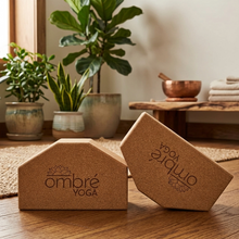 Load image into Gallery viewer, Tan cork angled yoga blocks with ombré yoga logo, shown on a wooden surface.